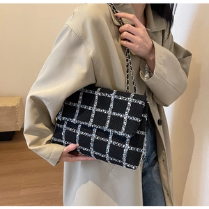 Détail d'un sac bandoulière en tweed à carreaux bleu et blanc avec chaîne dorée