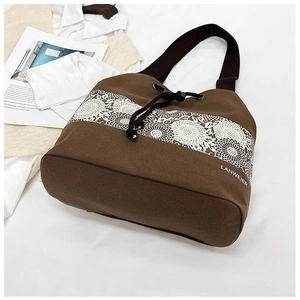 Close-up of brown canvas bucket bag with white lace ribbon detail and drawstring closure