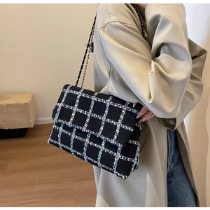 Détail d'un sac à bandoulière en tweed à carreaux noir et bleu avec chaîne métallique