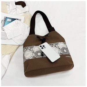 Detail of canvas bucket bag featuring daisy lace pattern and brown drawstring closure