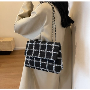 Sac à bandoulière en tweed à carreaux chic avec chaîne en métal porté par un mannequin
