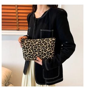 Close-up of stylish leopard print clutch bag held by model in modern lifestyle setting