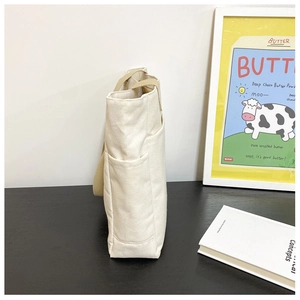 Détail du sac cabas en toile avec poche latérale et poignées tissées robustes