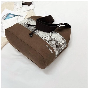 Detailed view of dark brown canvas tote bag with white lace floral print and strap