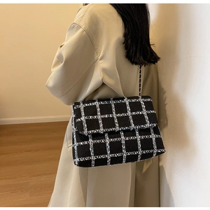 Sac bandoulière classique en tweed noir et blanc porté par un mannequin pour un style d'automne