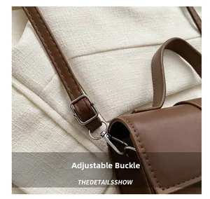 Détail de la boucle argentée réglable et de la bandoulière en cuir marron du sac rétro