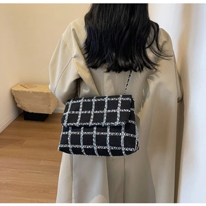 Détail du sac à bandoulière en tweed à carreaux avec chaîne porté par le modèle
