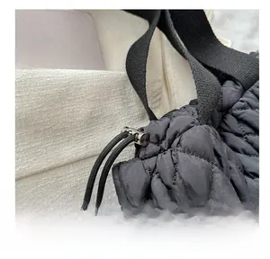 Detail einer schwarzen Stepptasche mit verstellbarem Kordelzug und Metallschnallen