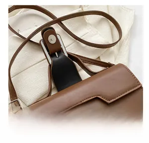 Détail du fermoir magnétique en métal sur un sac à bandoulière en cuir marron vintage
