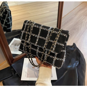 Détail de la texture en tweed noir et de la chaîne dorée sur un sac à bandoulière femme