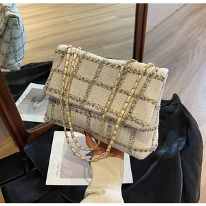 Détail du motif en tweed et de la bandoulière en chaîne dorée de ce sac à main chic