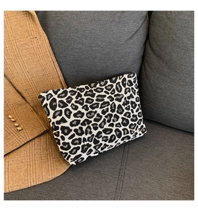 Detail of black and white leopard print pouch with woven texture on a gray sofa