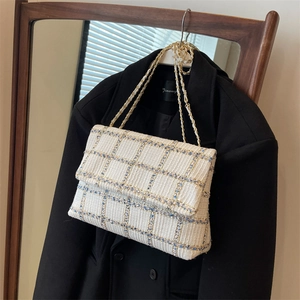 Sac bandoulière chic en tweed à carreaux avec chaîne dorée sur un blazer noir