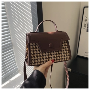 Detail einer Retro-Handtasche aus braunem Leder mit Hahnentrittmuster und Metallschnalle