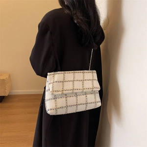 Sac bandoulière chic en tweed beige avec chaîne dorée porté par un mannequin en manteau