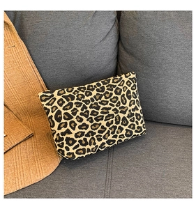 Detail shot of leopard print handbag with golden zipper on a gray sofa background