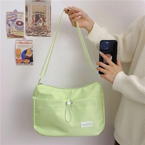 Close-up of mint green nylon bag featuring adjustable drawstring pocket and fashion label