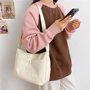 Close-up of beige nylon crossbody bag with drawstring pocket and fashion tag