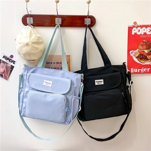 Detail of canvas tote bags with multiple pockets in light blue and black shown on hooks
