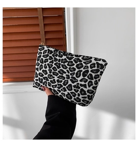 Detail shot of the sturdy leopard print canvas clutch featuring a sleek gold metal zipper