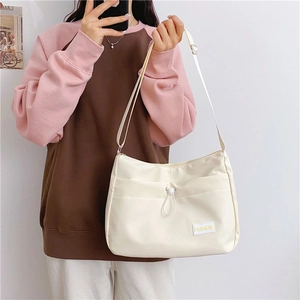 Detail view of cream crossbody bag featuring fashion patch and adjustable shoulder strap