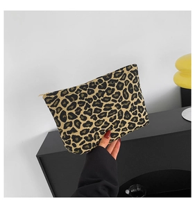 Close-up of leopard print clutch with golden zipper held by a person in a modern interior