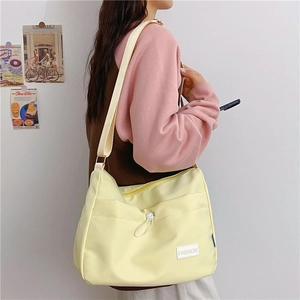Side view of a bright yellow messenger bag featuring a white Fashion patch and drawstring details