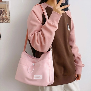 Detail of light pink nylon crescent bag with adjustable strap and fashion patch detail