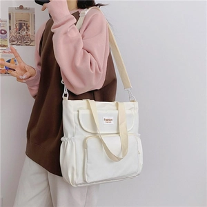 Detail view of large white canvas tote bag with side pockets and fashion label