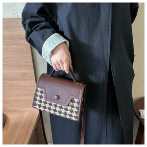 Detail der braunen Vintage-Handtasche mit Lederklappe und modischem Schachbrettmuster