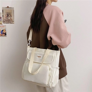 Detail view of white canvas tote bag with adjustable shoulder straps and side pockets