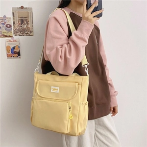 Detailed view of pale yellow canvas tote with multiple pockets and fashion label