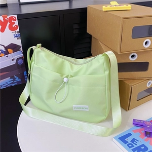 Detail of light green nylon dumpling bag showing drawstring pocket and fashion label