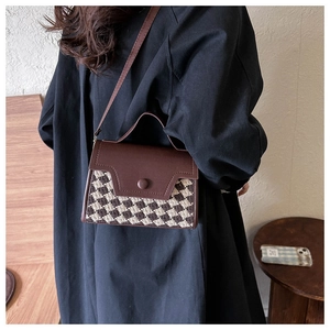 Nahaufnahme der Vintage-Umhängetasche aus Leder und Karostrick am Model-Outfit