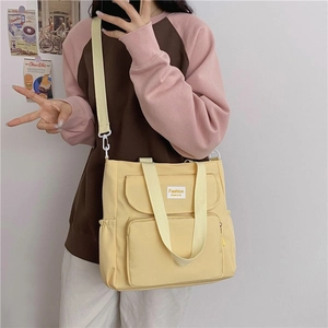 Detail of light yellow canvas tote bag featuring multi-pocket design and adjustable strap