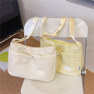 Close-up of beige and yellow nylon crossbody bags with drawstring front pockets