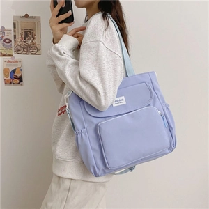 Detail view of lavender nylon tote bag featuring front flap pockets and side elastic pouches