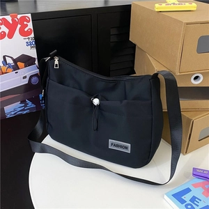 Detail of black nylon shoulder bag with a white drawstring pocket and fashion label