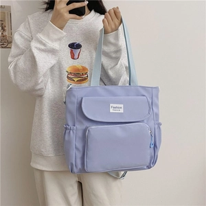 Detail view of light purple multi-pocket canvas tote bag worn by model showing storage capacity