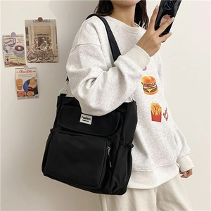 Detail of black large-capacity canvas crossbody bag with multiple pockets and drawstring side