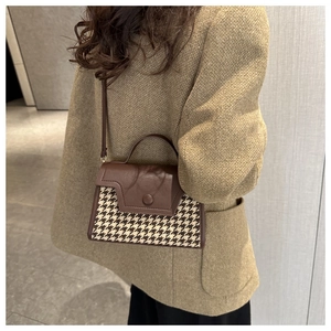 Nahaufnahme der Retro-Handtasche aus braunem Leder mit Hahnentrittmuster und Riemen