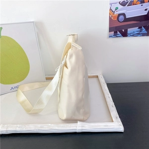 Side view of cream white minimalist crossbody dumpling bag with wide shoulder strap