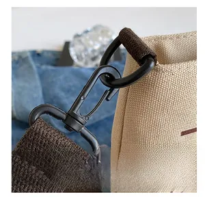 Detail showing durable black metal D-ring hook and woven shoulder strap on canvas tote