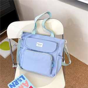 Detail view of light blue nylon tote bag with functional pockets and adjustable strap