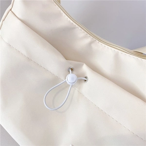 Detail of off-white nylon dumpling bag featuring silver eyelets and drawstring toggle