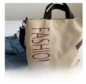 Detail of beige canvas tote with brown straps and vertical FASHION print detail
