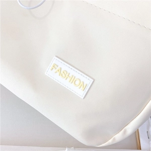 Close-up of the beige canvas fabric featuring a yellow 3D FASHION text patch detail