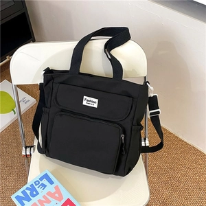 Detail view of large black nylon tote bag with multi-pocket design and adjustable strap