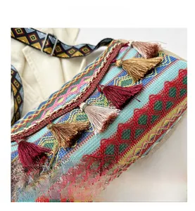Detail view of woven ethnic shoulder bag with embroidery and multi-color tassel accents