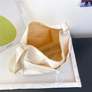 Interior view of cream nylon messenger bag showing spacious main zipper and inner pocket